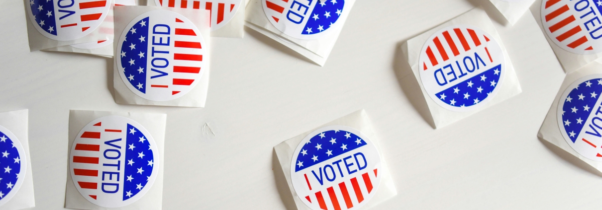 "I Voted" stickers are scattered on a white surface.