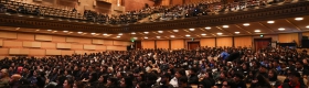conference attendees fill the interior of an auditorium.
