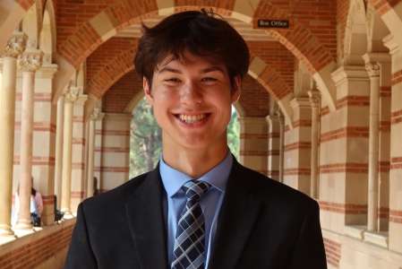 Nicholas Fong Neuweg stands under the arches in front of Royce Hall. He smiles directly at the camera.