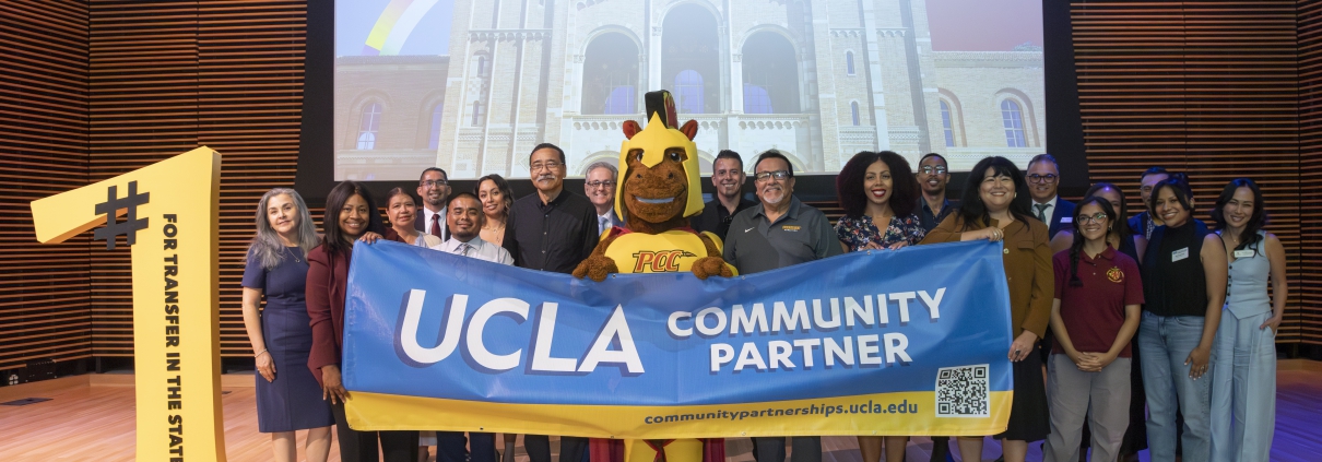 A group of people stands on stage holding a blue banner that reads "UCLA COMMUNITY PARTNER". A mascot stands in the center, and a large yellow cutout on the left reads "#1 FOR TRANSFER IN THE STATE / PASADENA CITY COLLEGE". A presentation screen behind them shows Royce Hall at UCLA along with UCLA and PCC logos.